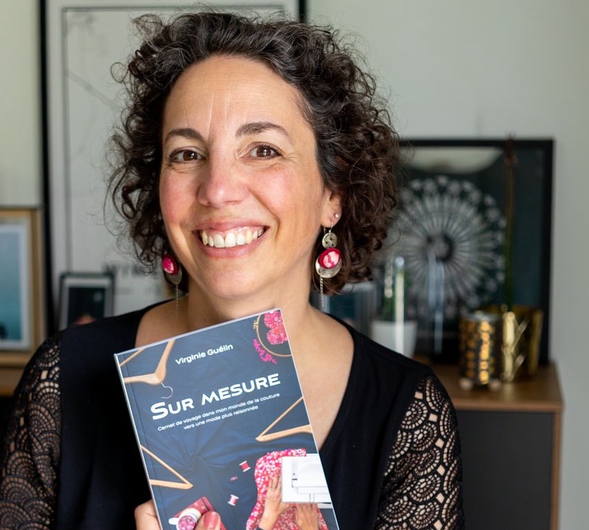 Virginie sourit, rayonnante et nous montre son livre "Sur mesure"